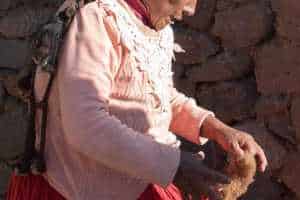 Indigenous Peruvian woman processing wool into yarn in her small house next to Sillustani Peru